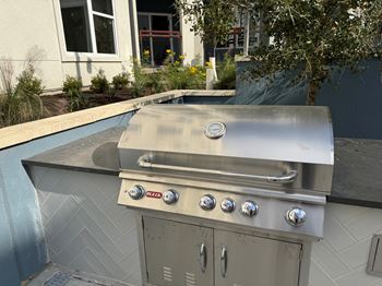 A stainless steel outdoor grill with four burners and a side burner.